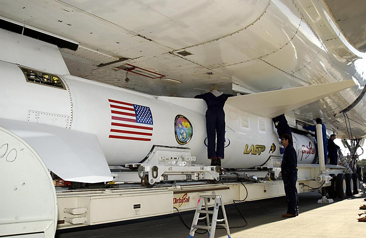 KENNEDY SPACE CENTER, FLA. - Technicians on Cape Canaveral Air Force Station, Fla., work to attach the Pegasus XL launch vehicle and Solar Radiation and Climate Experiment (SORCE) to the L-1011 aircraft. The L-1011 will carry the Pegasus to the launch altitude of 39,000 feet over the Atlantic Ocean approximately 100 miles east-southeast of Cape Canaveral. SORCE, built by Orbital Sciences Corporation, will study and measure solar irradiance as a source of energy in the Earth's atmosphere. The launch of SORCE is scheduled for Jan. 25 at 3:14 p.m. from CCAFS.