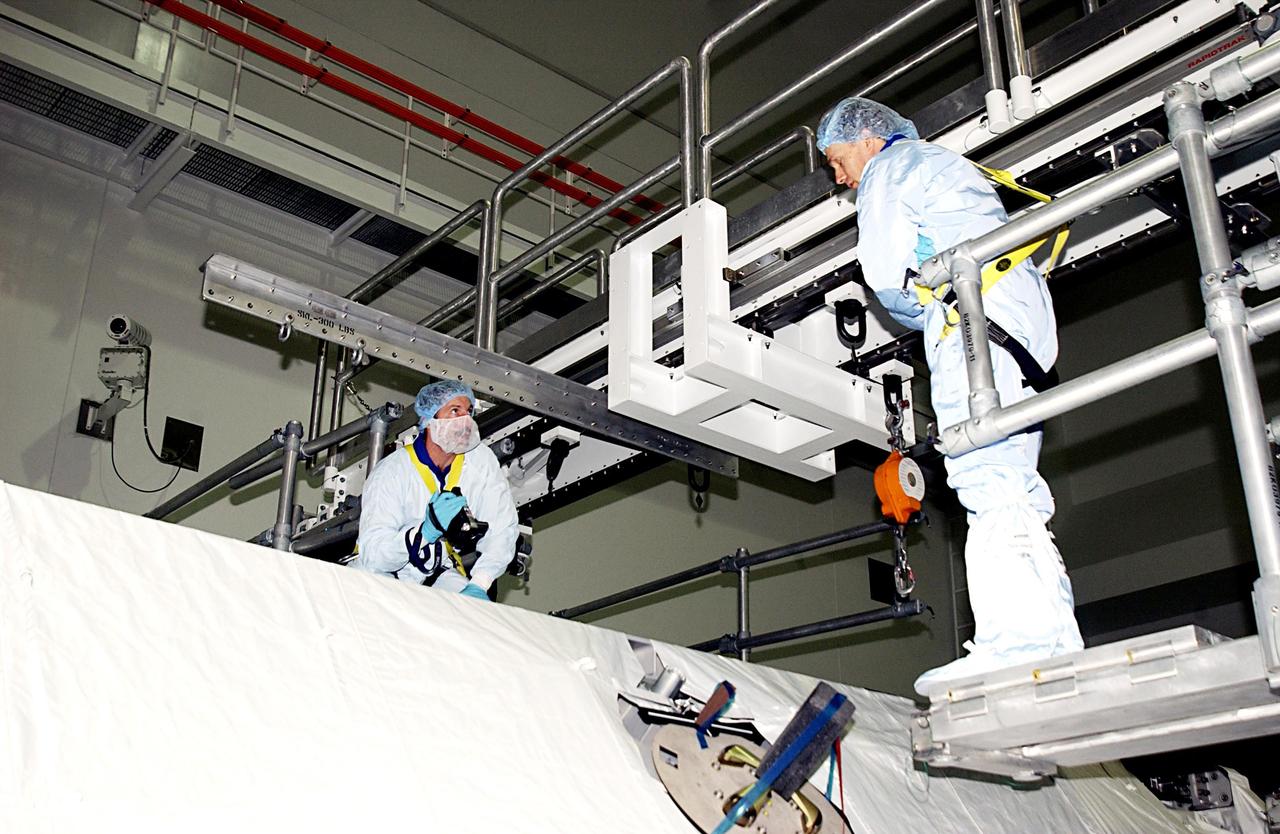 KENNEDY SPACE CENTER, FLA. -- In the Space Station Processing Facility, STS-115 Mission Specialists Daniel Burbank (left) and Steven MacLean (right) check out equipment during Crew Equipment Interface Test activities. MacLean is with the Canadian Space Agency.  The mission will deliver the second port truss segment, the P3/P4 Truss, to attach to the first port truss segment, the P1 Truss, as well as deploy solar array set 2A and 4A.  Launch on Space Shuttle Endeavour is scheduled for May 23, 2003.   