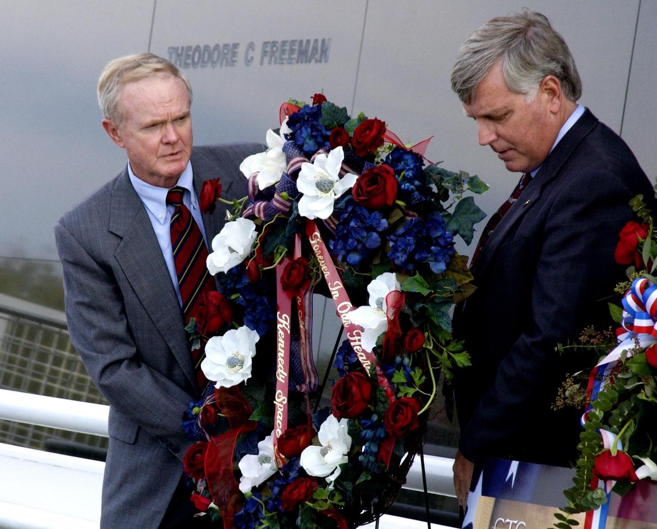 KENNEDY SPACE CENTER, FLA. - Following the tragic loss of Columbia and crew on their return to Earth, Center Director Roy Bridges and Deputy Director James Kennedy place a wreath in front of the Astronauts Memorial Space Mirror at the KSC Visitor Complex.  The mirror is a national tribute to the earlier 17 American astronauts who also gave their lives to the quest to explore space.  The site has been inundated with flowers from the public to honor the fallen crew of Columbia.  