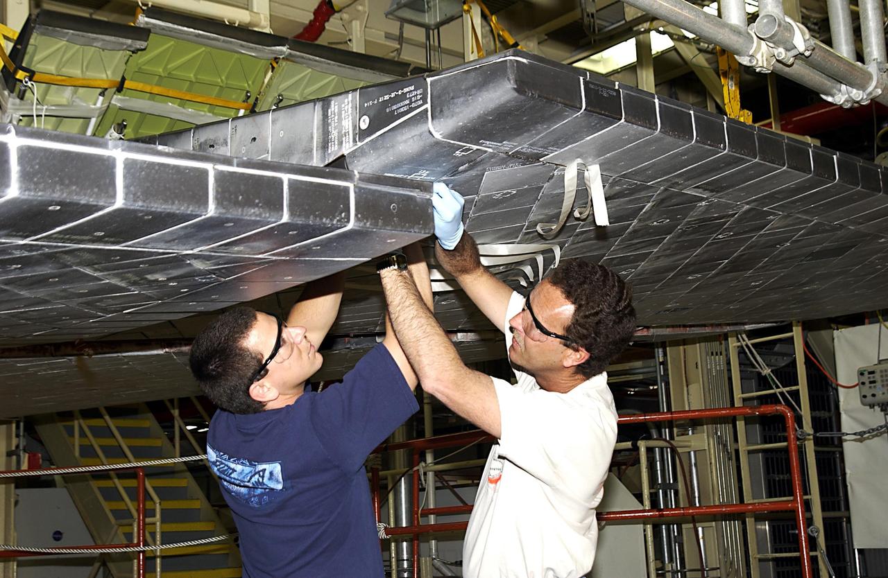KENNEDY SPACE CENTER, FLA. -- United Space Alliance (USA) technicians install thermal protection system tiles on Space Shuttle Discovery. Discovery is undergoing its Orbiter Major Modification Period, a regularly scheduled structural inspection and modification downtime, which began in September 2002. .