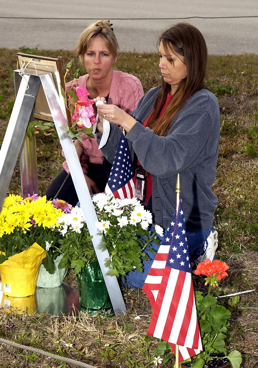KENNEDY SPACE CENTER, FLA. - At the corner of Contractors Road and the Saturn Causeway, KSC employees place an STS-107 crew photograph and surround it with flowers as a memorial tribute to the fallen crew of Columbia.  The Space Shuttle Columbia and her crew of seven were lost on Feb. 1, 2003, over East Texas as they returned to Earth after a 16-day research mission, STS-107.