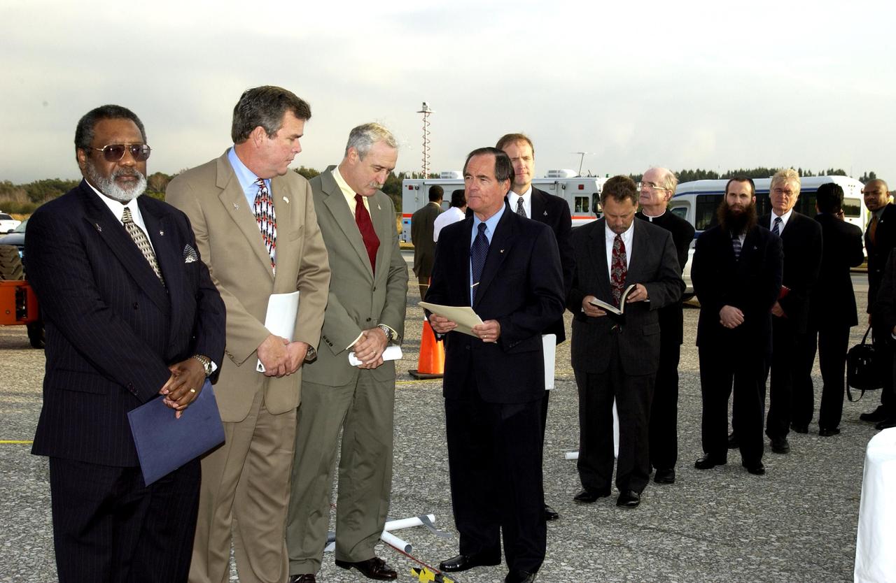 KENNEDY SPACE CENTER, FLA. -  A Columbia Crew Memorial Service is held at the Shuttle Landing Facility for KSC employees and invited guests, including (from left) NASA Associate Deputy Administrator for Institutions and Asset Management James L. Jennings, Florida Gov. Jeb Bush, NASA Administrator Sean O'Keefe, and Columbia's first pilot and former KSC Director Robert Crippen. The Columbia and her crew of seven were lost on Feb. 1, 2003, over East Texas as they returned to Earth after a 16-day research mission.  Taking part in the service were NASA Administrator Sean O’Keefe, former KSC Director Robert Crippen, astronaut Jim Halsell, several employees, area clergymen, and members of Patrick Air Force Base.  The service concluded with a “Missing Man Formation Fly Over” by NASA T-38 jet aircraft.
