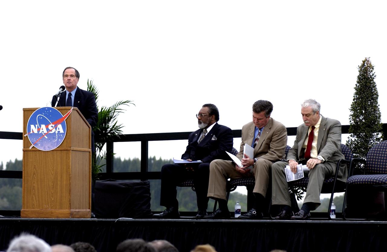 KENNEDY SPACE CENTER, FLA. -  A Columbia Crew Memorial Service is held at the Shuttle Landing Facility for KSC employees and invited guests. Columbia's first pilot and former KSC Director Robert Crippen is at the podium. Seated to his right are NASA Associate Deputy Administrator for Institutions and Asset Management James L. Jennings, Florida Gov. Jeb Bush, and NASA Administrator Sean O'Keefe. The Columbia and her crew of seven were lost on Feb. 1, 2003, over East Texas as they returned to Earth after a 16-day research mission.  Taking part in the service were NASA Administrator Sean O’Keefe, former KSC Director Robert Crippen, astronaut Jim Halsell, several employees, area clergymen, and members of Patrick Air Force Base.  The service concluded with a “Missing Man Formation Fly Over” by NASA T-38 jet aircraft.