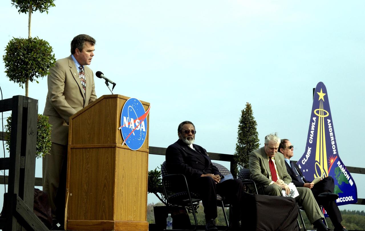 KENNEDY SPACE CENTER, FLA. -  A Columbia Crew Memorial Service is held at the Shuttle Landing Facility for KSC employees and invited guests.  Florida Gov. Jeb Bush is at the podium. Seated to his right are NASA Associate Deputy Administrator for Institutions & Asset Management James L. Jennings, NASA Administrator Sean O'Keefe, and Columbia's first pilot and former KSC Director Robert Crippen. The Columbia and her crew of seven were lost on Feb. 1, 2003, over East Texas as they returned to Earth after a 16-day research mission.  Taking part in the service were NASA Administrator Sean O’Keefe, former KSC Director Robert Crippen, astronaut Jim Halsell, several employees, area clergymen, and members of Patrick Air Force Base.  The service concluded with a “Missing Man Formation Fly Over” by NASA T-38 jet aircraft.