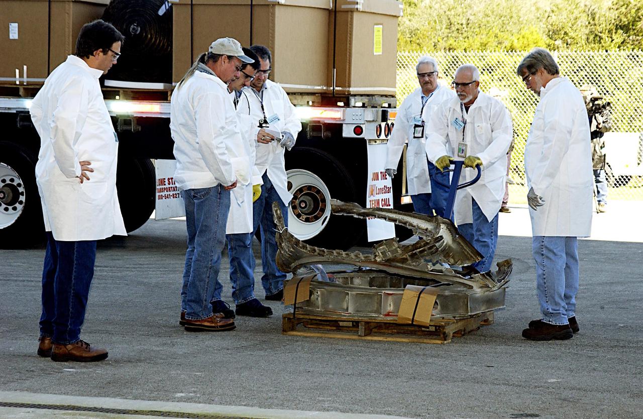 KENNEDY SPACE CENTER, FLA. - Workers look at a piece of the Columbia debris ready to be moved into the RLV Hangar near the Shuttle Landing Facility. Truckloads of the debris arrived from the collection point at Barksdale Air Force Base, Shreveport, La. The workers will attempt to reconstruct the orbiter as part of the ongoing investigation of the accident that destroyed the Columbia and claimed the lives of seven astronauts as they returned to Earth after a 16-day research mission, STS-107.