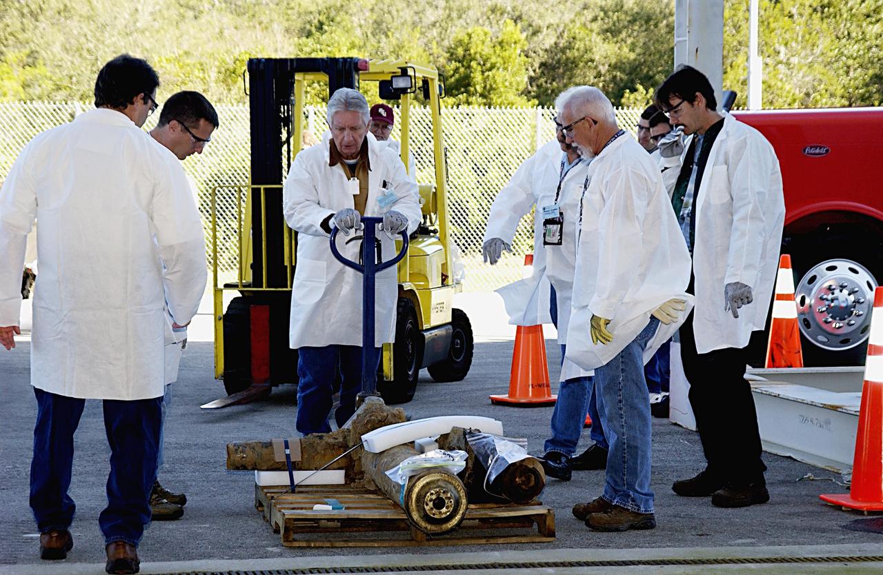 KENNEDY SPACE CENTER, FLA. -- Workers look at a piece of the Columbia debris ready to be moved into the RLV Hangar near the Shuttle Landing Facility. Truckloads of the debris arrived from the collection point at Barksdale Air Force Base, Shreveport, La. The workers will attempt to reconstruct the orbiter as part of the ongoing investigation of the accident that destroyed the Columbia and claimed the lives of seven astronauts as they returned to Earth after a 16-day research mission, STS-107.