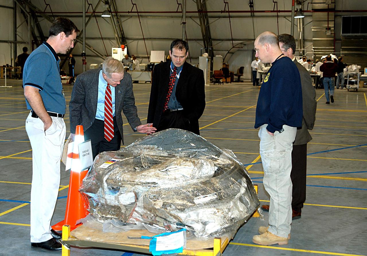 KENNEDY SPACE CENTER, FLA. - KSC Director Roy D. Bridges (second from left) inspects Columbia debris arriving at KSC from the collection point at Barksdale Air Force Base, Shreveport, La.  The debris is being collected at the RLV Hangar near the Shuttle Landing Facility.  Workers there will attempt to reconstruct the orbiter as part of the ongoing investigation of the accident that destroyed the Columbia and claimed the lives of seven astronauts as they returned to Earth after a 16-day research mission, STS-107.
