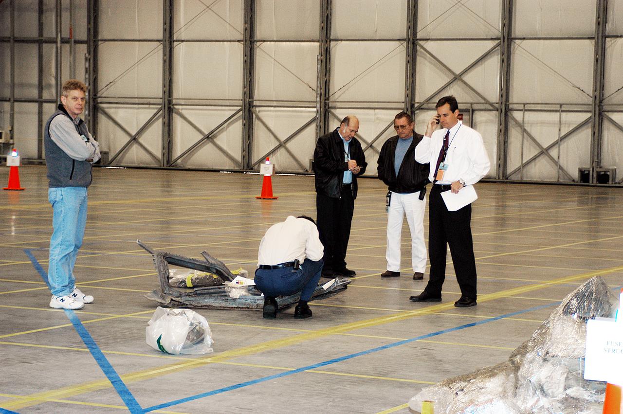 A worker examines a piece of the Columbia debris on the floor of the RLV Hangar. The debris was shipped from Barksdale Air Force Base, Shreveport, La. As part of the ongoing investigation into the tragic accident, workers will attempt to reconstruct the orbiter inside the RLV. 