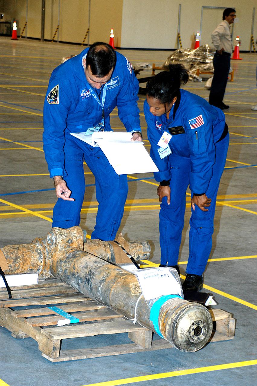 Astronauts Lee Archambault and Joan Higginbotham look at a piece of Columbia debris placed on the grid in the RLV Hangar. The debris was shipped from Barksdale Air Force Base, Shreveport, La. As part of the ongoing investigation into the tragic accident, workers will attempt to reconstruct the orbiter inside the RLV. 