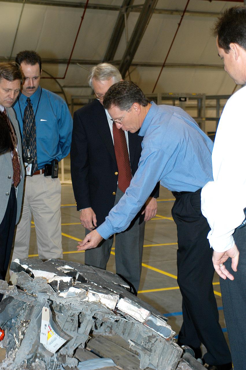 Shuttle Program Manager Ron Dittemore (leaning over) examines a piece of Columbia debris in the RLV Hangar. The debris was shipped from the collection point at Barksdale Air Force Base, Shreveport, La. As part of the ongoing investigation into the tragic accident that claimed Columbia and her crew of seven, workers will attempt to reconstruct the orbiter inside the RLV.               