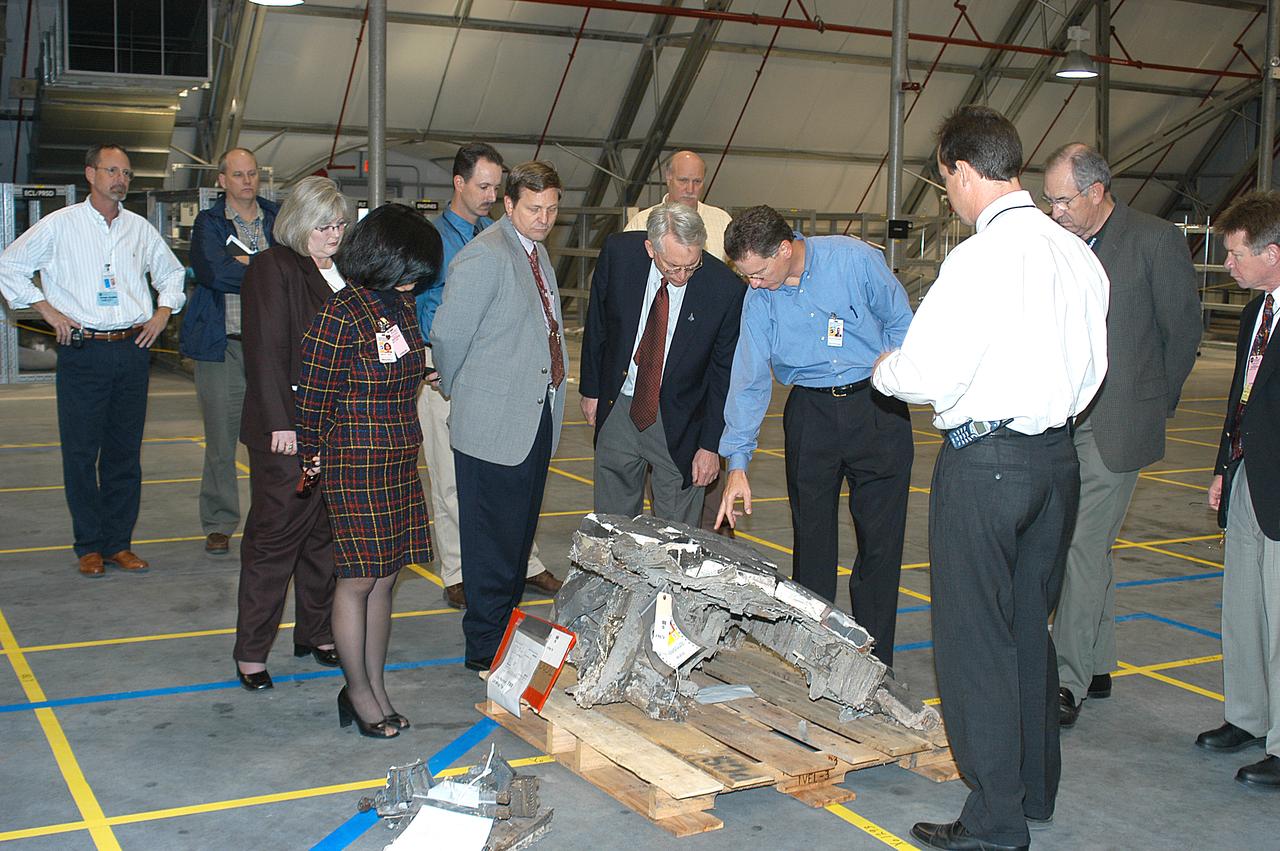Shuttle Program Manager Ron Dittemore (leaning over) examines a piece of Columbia debris in the RLV Hangar. The debris was shipped from the collection point at Barksdale Air Force Base, Shreveport, La. As part of the ongoing investigation into the tragic accident that claimed Columbia and her crew of seven, workers will attempt to reconstruct the orbiter inside the RLV.