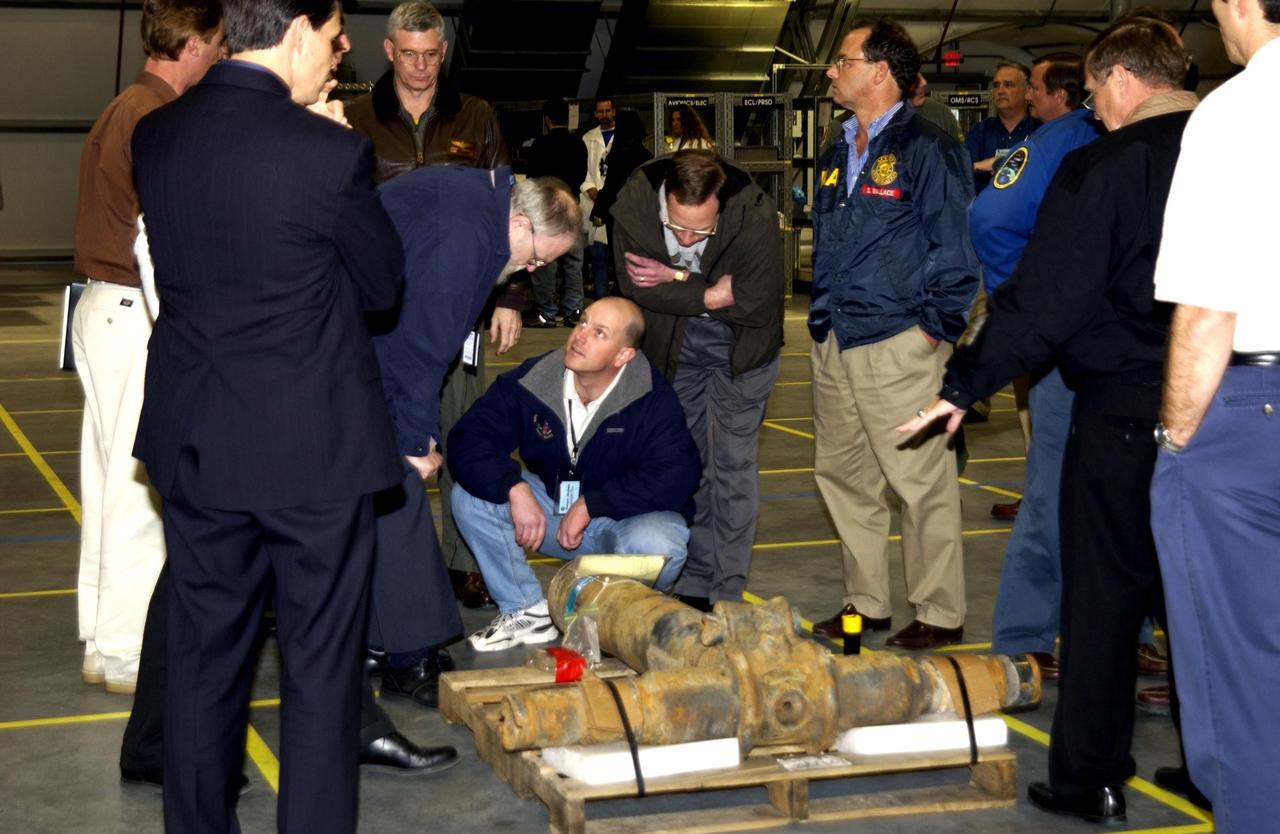KENNEDY SPACE CENTER, FLA. --  Members of the Columbia Accident Investigation Board examine a piece of Columbia debris in the RLV Hangar. The debris was shipped from the collection point at Barksdale Air Force Base, Shreveport, La.  As part of the ongoing investigation into the tragic accident that claimed Columbia and her crew of seven, workers will attempt to reconstruct the orbiter inside the RLV.