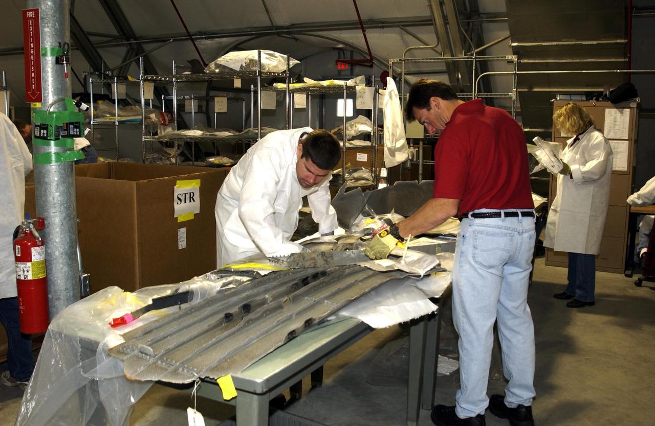 KENNEDY SPACE CENTER, FLA. -- In the RLV Hangar, Columbia Reconstruction Project Team members examine a piece of debris from the Space Shuttle Columbia. The debris has begun arriving at KSC from the collection point at Barksdale Air Force Base, Shreveport, La. As part of the ongoing investigation into the tragic accident that claimed Columbia and her crew of seven, workers will attempt to reconstruct the orbiter inside the hangar.