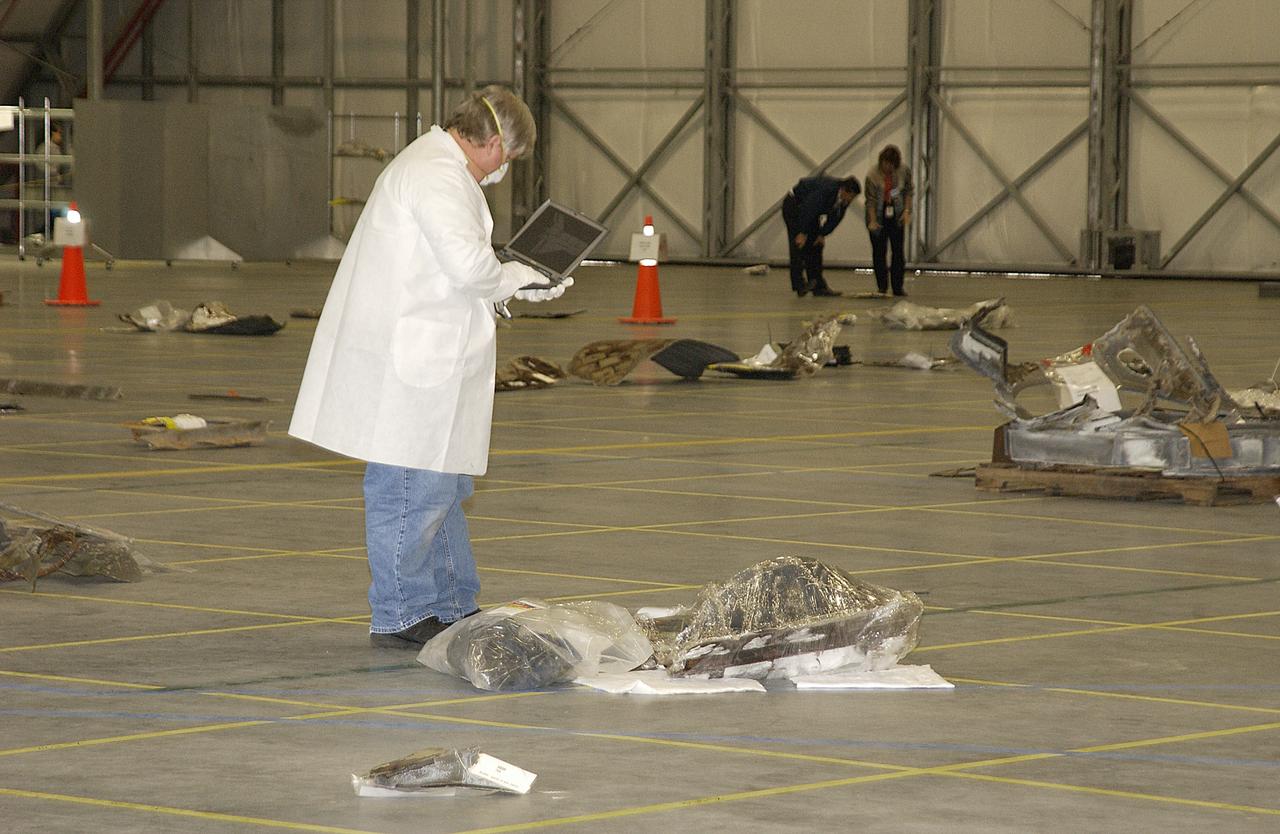 In the RLV Hangar, a Columbia Reconstruction Project Team member examines pieces of debris from the Space Shuttle Columbia. The debris has begun arriving at KSC from the collection point at Barksdale Air Force Base, Shreveport, La. As part of the ongoing investigation into the tragic accident that claimed Columbia and her crew of seven, workers will attempt to reconstruct the orbiter inside the hangar.