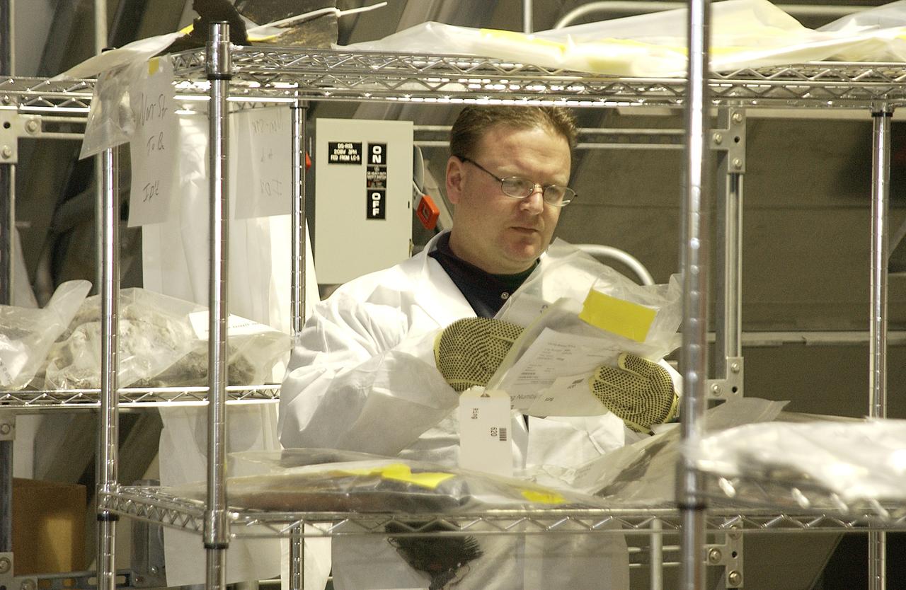 In the RLV Hangar, a Columbia Reconstruction Project Team member examines a piece of debris from the Space Shuttle Columbia. The debris has begun arriving at KSC from the collection point at Barksdale Air Force Base, Shreveport, La. As part of the ongoing investigation into the tragic accident that claimed Columbia and her crew of seven, workers will attempt to reconstruct the orbiter inside the hangar.