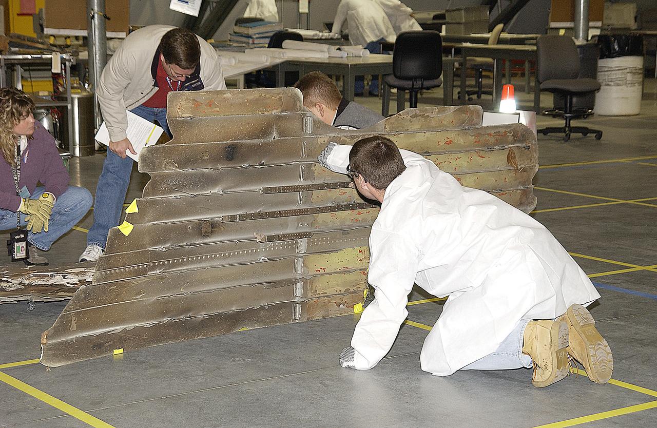 Columbia Reconstruction Project Team members steady a piece of debris from the Space Shuttle Columbia as they position it in a designated sector of the RLV Hangar. The debris is being shipped to KSC from the collection point at Barksdale Air Force Base, Shreveport, La. As part of the ongoing investigation into the tragic accident that claimed Columbia and her crew of seven, workers will attempt to reconstruct the orbiter inside the hangar.