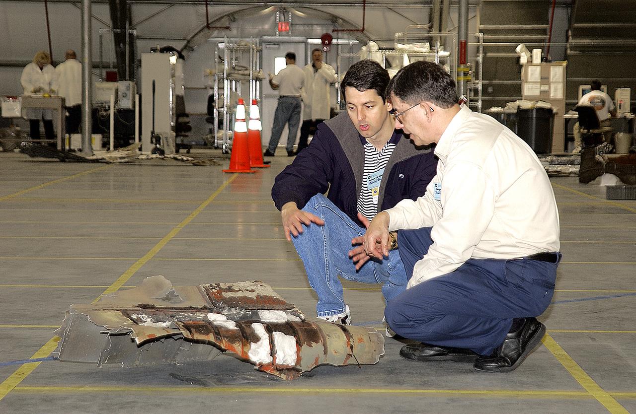 Columbia Reconstruction Project Team members examine a piece of debris from the Space Shuttle Columbia in the RLV Hangar. The debris is being shipped to KSC from the collection point at Barksdale Air Force Base, Shreveport, La. As part of the ongoing investigation into the tragic accident that claimed Columbia and her crew of seven, workers will attempt to reconstruct the orbiter inside the hangar.