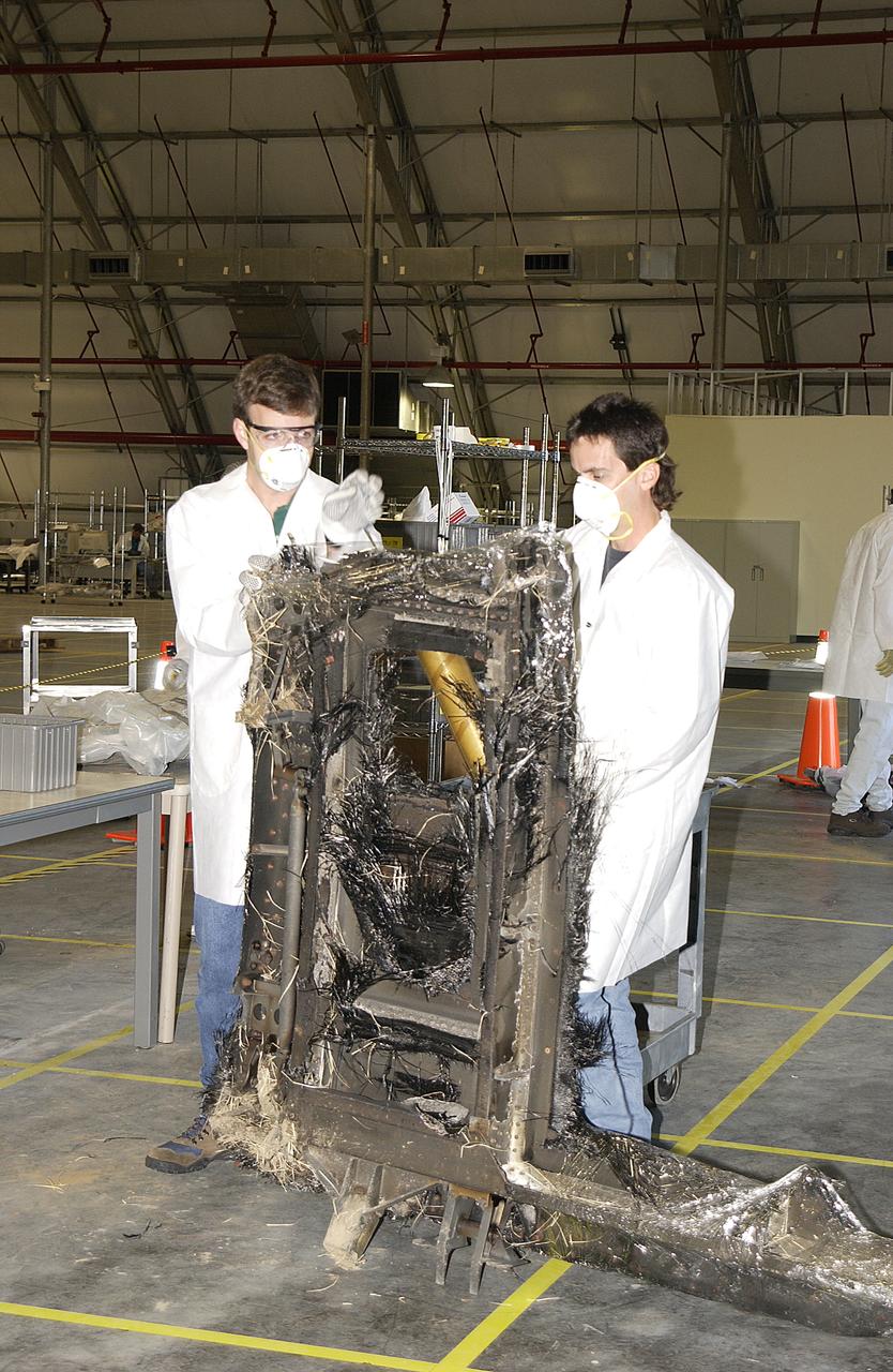 Columbia Reconstruction Project Team members move a piece of debris from the Space Shuttle Columbia into a specified sector of the RLV Hangar. The debris is being shipped to KSC from the collection point at Barksdale Air Force Base, Shreveport, La. As part of the ongoing investigation into the tragic accident that claimed Columbia and her crew of seven, workers will attempt to reconstruct the orbiter inside the hangar.