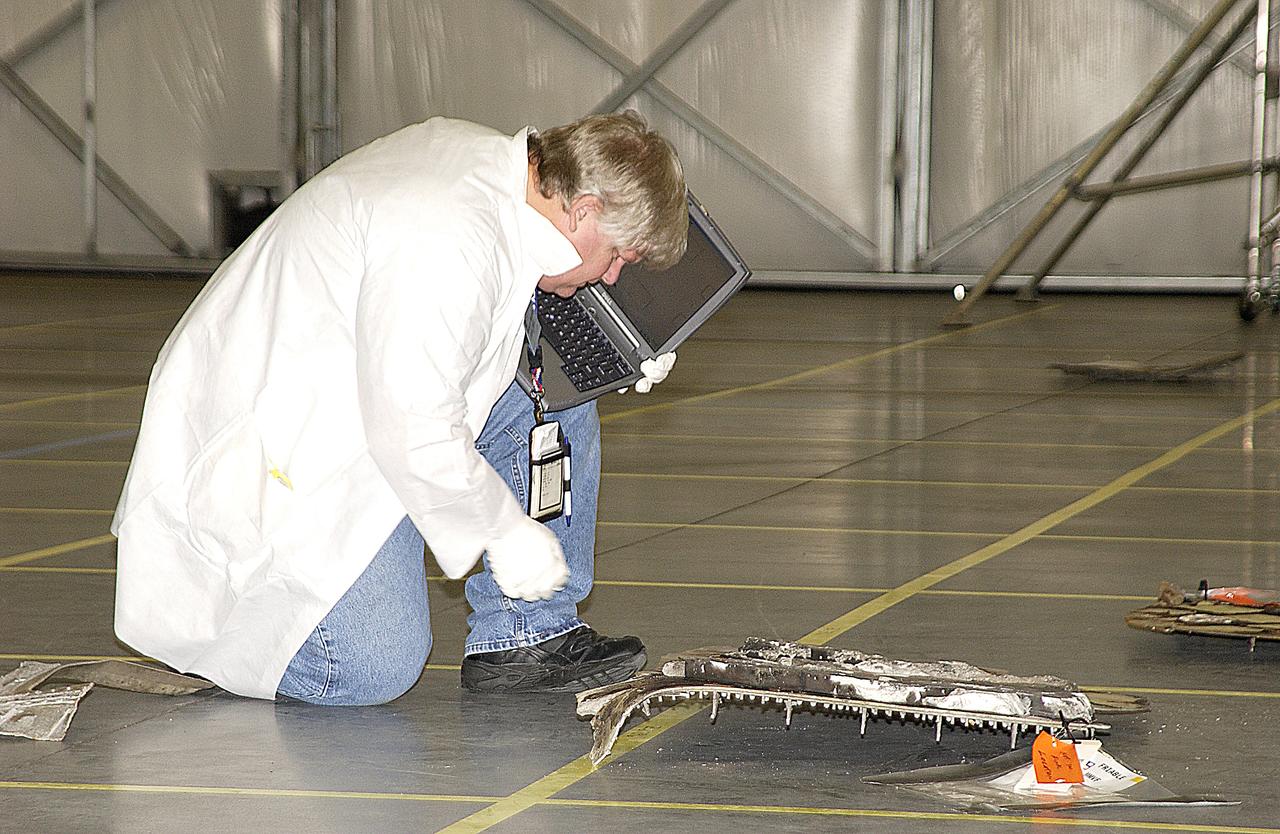 A Columbia Reconstruction Project Team member uses a laptop computer to catalog debris from the Space Shuttle Columbia in the RLV Hangar. The debris is being shipped to KSC from the collection point at Barksdale Air Force Base, Shreveport, La. As part of the ongoing investigation into the tragic accident that claimed Columbia and her crew of seven, workers will attempt to reconstruct the orbiter inside the hangar.