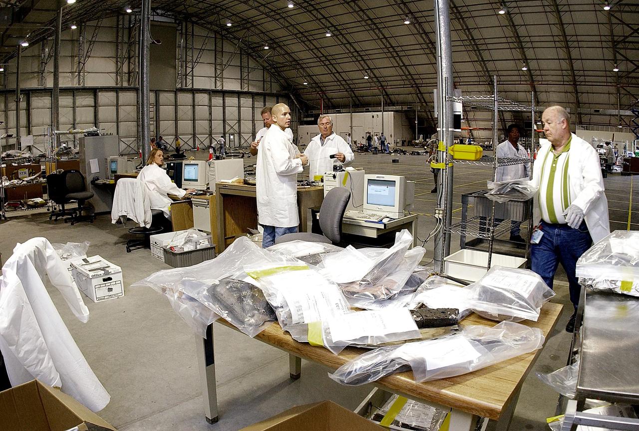 KENNEDY SPACE CENTER, FLA. -- Columbia Reconstruction Project Team members examine pieces of debris from the Space Shuttle Columbia for cataloging in the RLV Hangar. The debris is being shipped to KSC from the collection point at Barksdale Air Force Base, Shreveport, La. As part of the ongoing investigation into the tragic accident that claimed Columbia and her crew of seven, workers will attempt to reconstruct the orbiter inside the hangar.