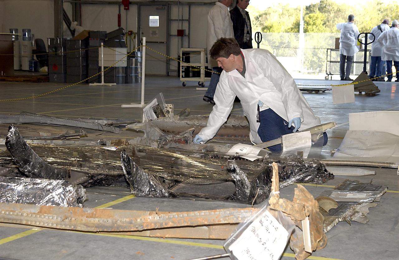 KENNEDY SPACE CENTER, FLA. -- A Columbia Reconstruction Project Team member examines pieces of debris from the Space Shuttle Columbia in the RLV Hangar. The debris arrived at KSC today from the collection point at Barksdale Air Force Base, Shreveport, La. As part of the ongoing investigation into the tragic accident that claimed Columbia and her crew of seven, workers will attempt to reconstruct the orbiter inside the hangar.