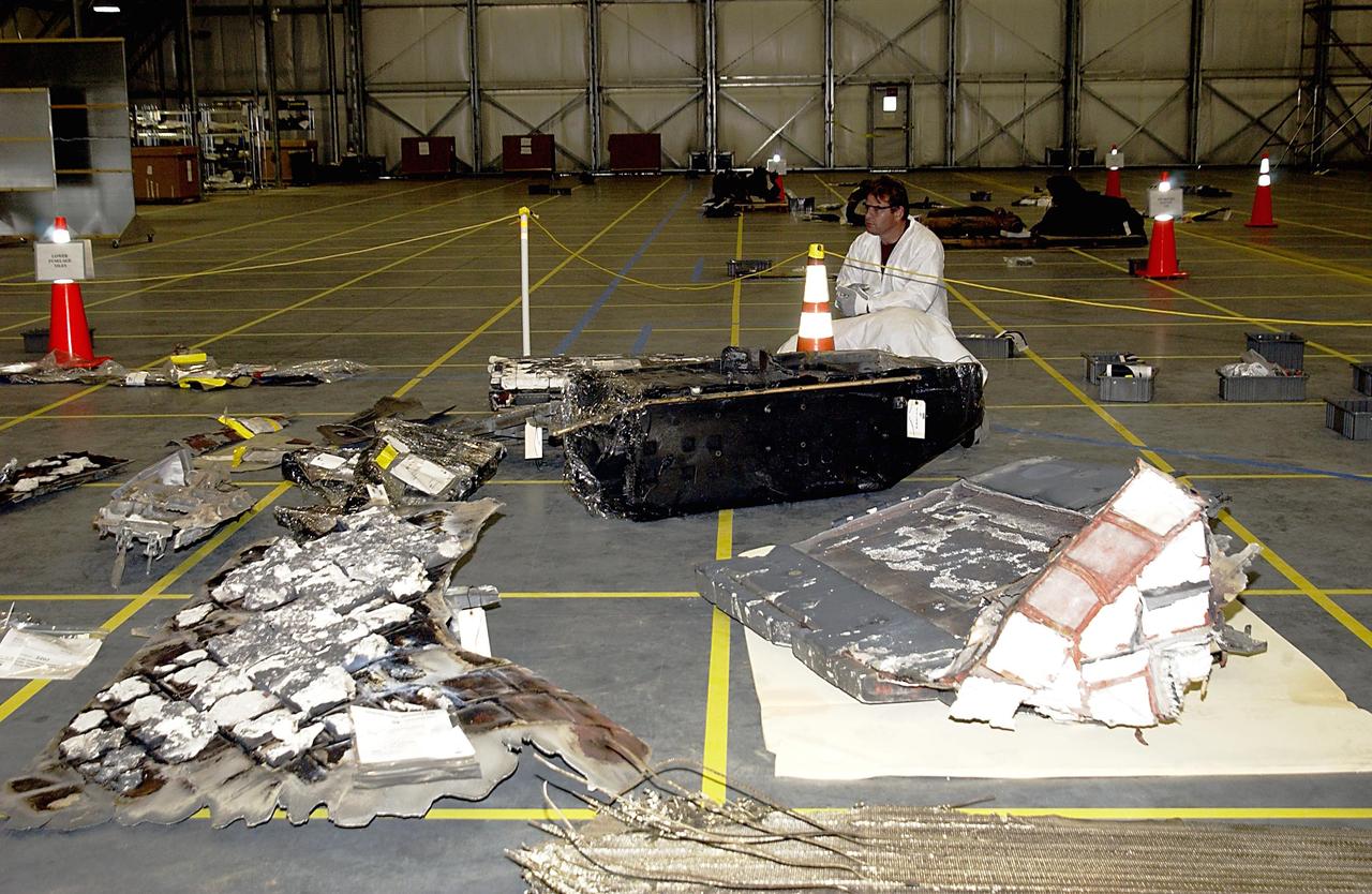 KENNEDY SPACE CENTER, FLA. -- A Columbia Reconstruction Project Team member surveys pieces of debris from the Space Shuttle Columbia in the RLV Hangar. The debris arrived at KSC today from the collection point at Barksdale Air Force Base, Shreveport, La. As part of the ongoing investigation into the tragic accident that claimed Columbia and her crew of seven, workers will attempt to reconstruct the orbiter inside the hangar.