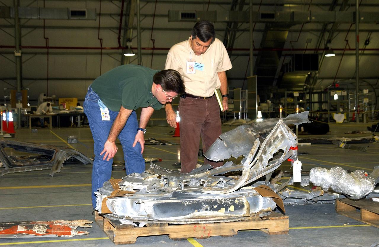 KENNEDY SPACE CENTER, FLA. -- Columbia Reconstruction Project Team members examine newly arrived pieces of debris from the Space Shuttle Columbia in the RLV Hangar. The debris was shipped to KSC from the collection point at Barksdale Air Force Base, Shreveport, La. As part of the ongoing investigation into the tragic accident that claimed Columbia and her crew of seven, workers will attempt to reconstruct the orbiter inside the hangar.