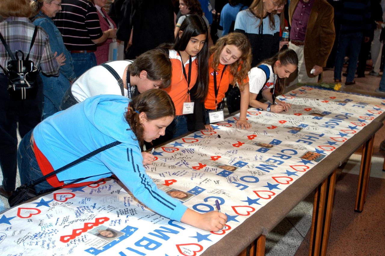 KENNEDY SPACE CENTER, FLA. -- At the Sally Ride Science Festival, held at the University of Central Florida, Orlando, Fla., young women gather to sign a large poster in tribute to the Columbia astronauts who were lost in the Shuttle's explosion the day before. The Sally Ride event promotes science, math and technology as future career paths for girls. Former astronaut Sally Ride addressed the girls, while breakout sessions afforded closer interaction between Ride and festival attendees.
