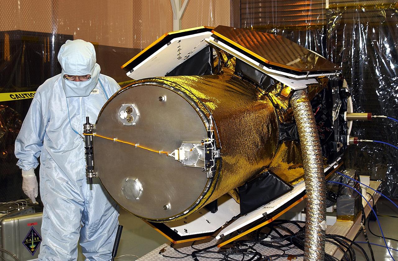KENNEDY SPACE CENTER, FLA. -- In the Multi-Payload Processing Facility, workers check the deployment of the cover of the telescope on the GALEX satellite. The Galaxy Evolution Explorer (GALEX) is an orbiting space telescope that will observe galaxies in ultraviolet light across 10 billion years of cosmic history. Led by the California Institute of Technology, GALEX will conduct several first-of-a-kind sky surveys, including an extra-galactic (beyond our galaxy) ultraviolet all-sky survey. During its 29-month mission GALEX will produce the first comprehensive map of a Universe of galaxies under construction, bringing more understanding of how galaxies like the Milky Way were formed. GALEX is due to be launched from Cape Canaveral Air Force Station March 25 via a Pegasus rocket.