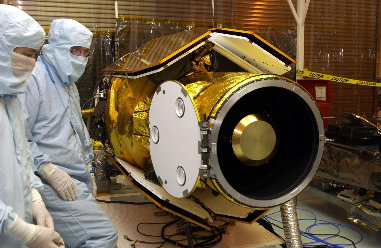 KENNEDY SPACE CENTER, FLA. -- In the Multi-Payload Processing Facility, workers check the deployment of the cover of the telescope on the GALEX satellite. The Galaxy Evolution Explorer (GALEX) is an orbiting space telescope that will observe galaxies in ultraviolet light across 10 billion years of cosmic history. Led by the California Institute of Technology, GALEX will conduct several first-of-a-kind sky surveys, including an extra-galactic (beyond our galaxy) ultraviolet all-sky survey. During its 29-month mission GALEX will produce the first comprehensive map of a Universe of galaxies under construction, bringing more understanding of how galaxies like the Milky Way were formed.  GALEX is due to be launched from Cape Canaveral Air Force Station March 25 via a Pegasus rocket.