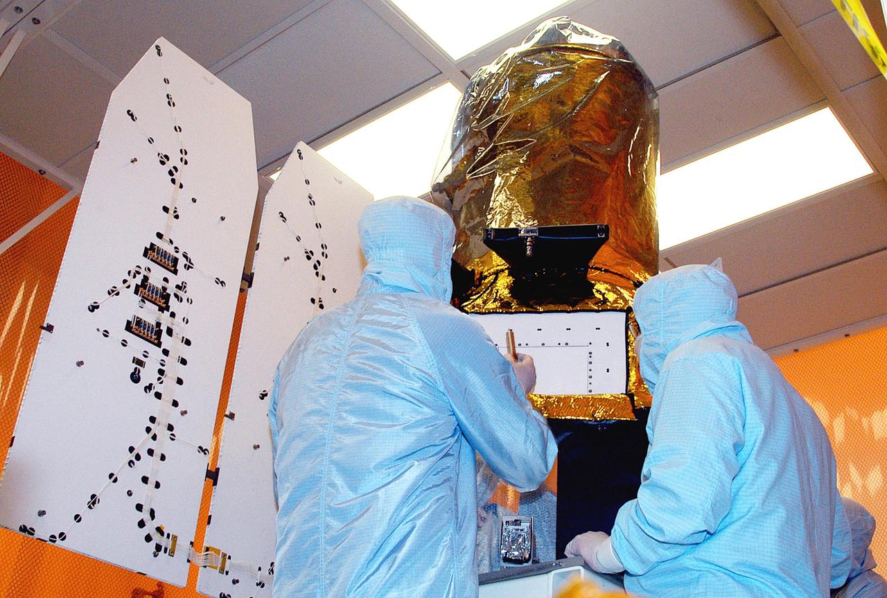 KENNEDY SPACE CENTER, FLA. -- Workers in the Multi-Payload Processing Facility check the solar array panels on the Galaxy Evolution Explorer (GALEX) satellite after they were deployed. The GALEX is an orbiting space telescope that will observe galaxies in ultraviolet light across 10 billion years of cosmic history. Led by the California Institute of Technology, GALEX will conduct several first-of-a-kind sky surveys, including an extra-galactic (beyond our galaxy) ultraviolet all-sky survey. During its 29-month mission GALEX will produce the first comprehensive map of a Universe of galaxies under construction, bringing more understanding of how galaxies like the Milky Way were formed.  GALEX is due to be launched from Cape Canaveral Air Force Station March 25 via a Pegasus rocket.