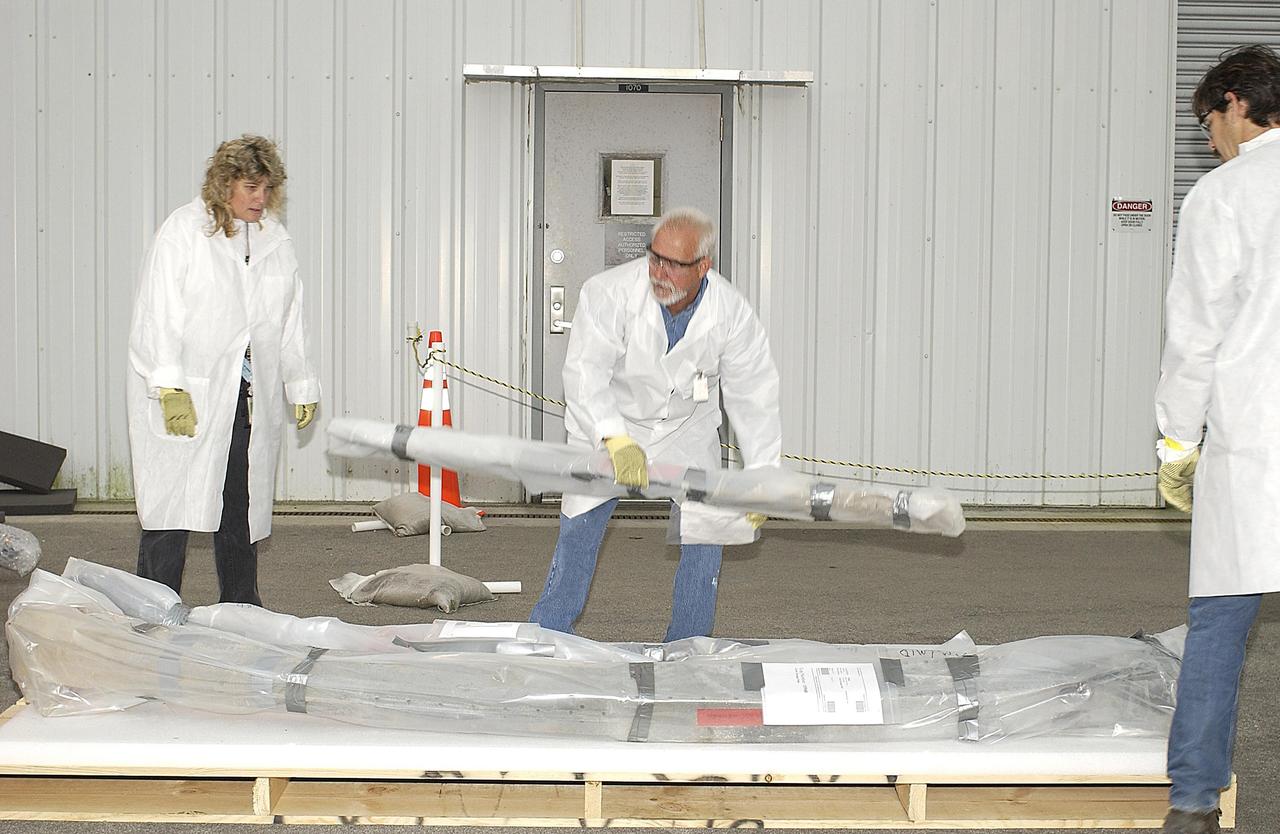 KENNEDY SPACE CENTER, FLA. --  A member of the Columbia Restoration Project Team places a piece of debris on the floor of the RLV Hangar at KSC.  A fourth shipment of Columbia debris has arrived at KSC.  The team is examining pieces and attempting to reconstruct the orbiter as part of the investigation into the accident that caused the destruction of Columbia as it returned to Earth on mission STS-107.  To date, four shipments have arrived from Barksdale AFB, Shreveport, La., the collection point for debris.