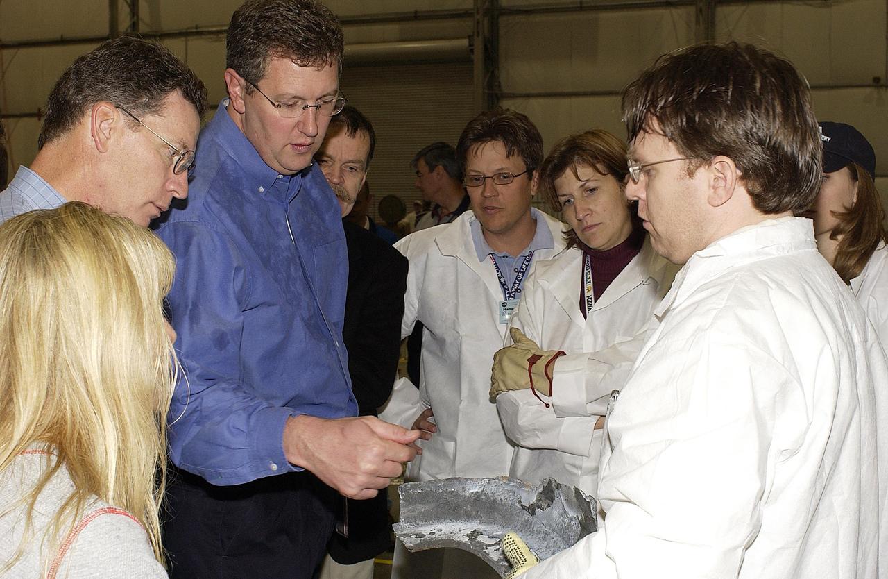KENNEDY SPACE CENTER, FLA. -- Shuttle Program Manager Ron Dittemore (second from left) and Ralph Roe, (third from left), with the Orbiter Work Group, JSC, examine a piece of debris from Columbia. A Columbia Restoration Project Team is examining pieces and attempting to reconstruct the orbiter as part of the investigation into the accident that caused the destruction of Columbia on its return to Earth from mission STS-107. To date, four shipments have arrived from Barksdale AFB, Shreveport, La., the collection point for debris.