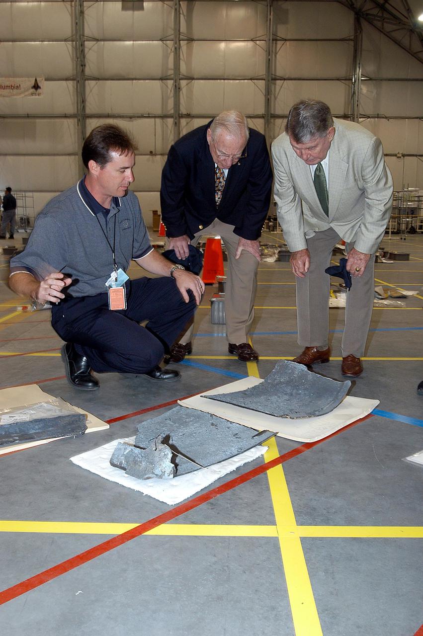 KENNEDY SPACE CENTER, FLA. - In the RLV Hangar, Space Shuttle Test Director Steve Altemus (left) shows former astronauts Jim Lovell (center) and Wally Schirra (right) a piece of debris from Columbia. The latter two visited several sites around the Center, encouraging workers to help get the space program "back on its feet."  The RLV Hangar is where Columbia debris is being collected and examined as part of the investigation into the tragedy that claimed the orbiter and lives of seven astronauts returning from mission STS-107.
