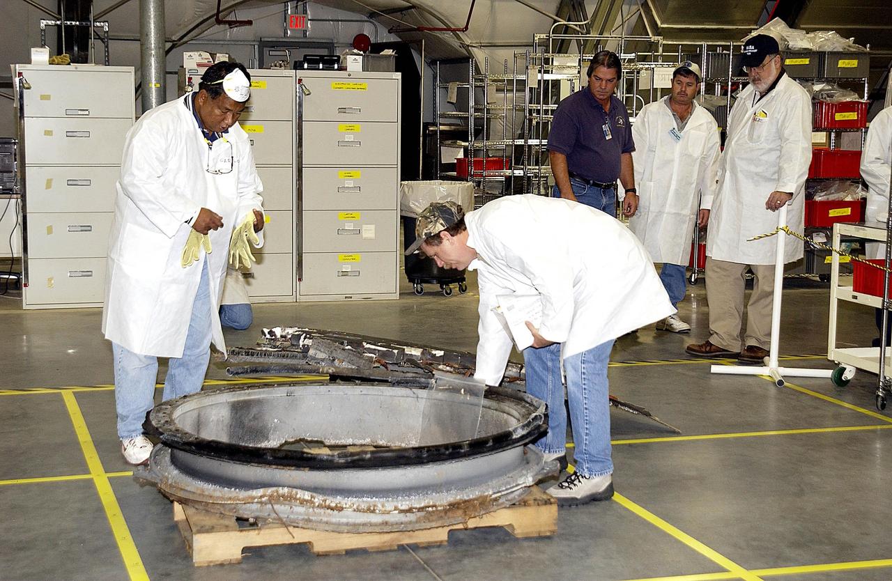 KENNEDY SPACE CENTER, FLA. - In the RLV Hangar, members of the Columbia Reconstruction Project Team look at a piece of Columbia debris shipped from Barksdale AFB, Shreveport, La.  Barksdale continues to be the receiving and shipping point for Columbia materials being sent to KSC for final identification.  Inside the RLV Hangar, the Columbia Reconstruction Project Team will attempt to reconstruct the orbiter as part of the investigation into the accident that caused the destruction of Columbia and loss of its crew as it returned to Earth on mission STS-107.
