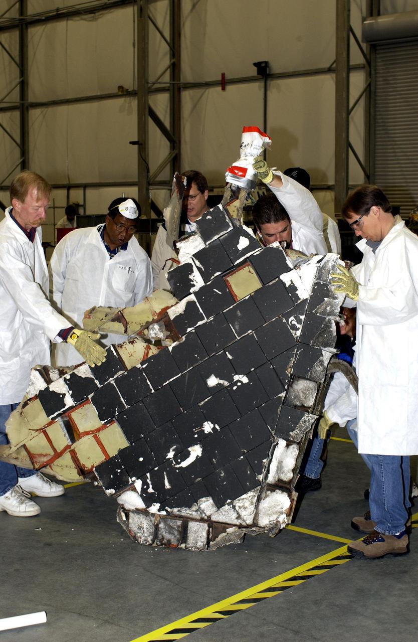 KENNEDY SPACE CENTER, FLA. -- In the RLV Hangar, members of the Columbia Reconstruction Project Team examine a large piece of Columbia debris shipped from Barksdale AFB, Shreveport, La.  Barksdale continues to be the receiving and shipping point for Columbia materials being sent to KSC for final identification.  The team is attempting to reconstruct the orbiter as part of the investigation into the accident that caused the destruction of Columbia and loss of its crew as it returned to Earth on mission STS-107.