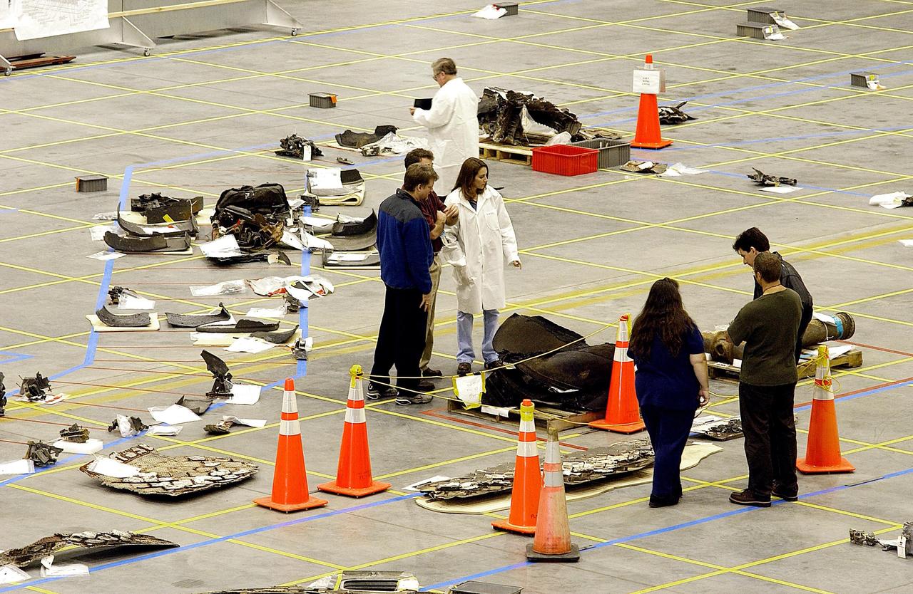 KENNEDY SPACE CENTER, FLA. -- In the RLV Hangar, members of the Columbia Reconstruction Project Team look at Columbia debris placed on the floor grid.  The team is attempting to reconstruct the orbiter as part of the investigation into the accident that caused the destruction of Columbia and loss of its crew as it returned to Earth on mission STS-107.
