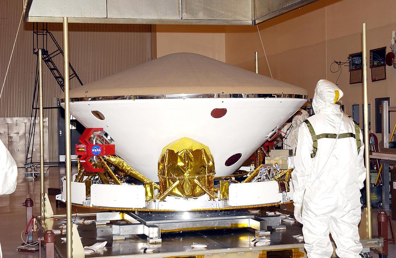 KENNEDY SPACE CENTER, FLA. --  With the shipping container lifted, the aeroshell and cruise stage of Mars Exploration Rover-1 are revealed in the Payload Hazardous Servicing Facility.  The upper portion is the heat shield on the aeroshell. Each rover , aeroshell and lander will undergo a full mission simulation while at KSC.  All flight elements will then be integrated.  After spin balance testing, each spacecraft will be mated to a solid propellant upper stage booster that will propel it out of Earth orbit.  The rovers will serve as robotic geologists to seek answers about the evolution of Mars, particularly  for a history of water. The rovers will be identical to each other, but will land at different regions of Mars.  Launch of the MER-1 is scheduled for May 30.  MER-2 will follow June 25.