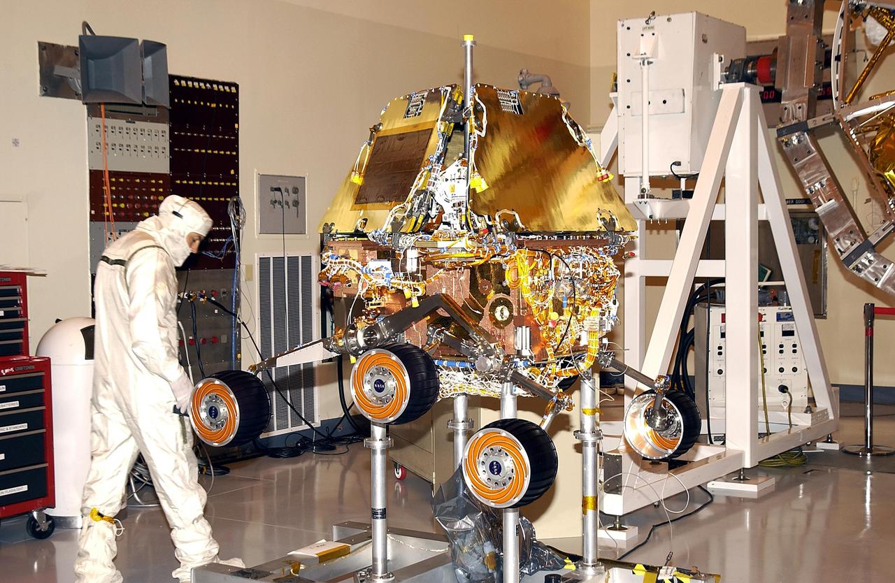 KENNEDY SPACE CENTER, FLA. --  A worker in the Payload Hazardous Servicing Facility looks closely at the Mars Exploration Rover-2. Each rover , aeroshell and lander will undergo a full mission simulation while at KSC.  All flight elements will then be integrated.  After spin balance testing, each spacecraft will be mated to a solid propellant upper stage booster that will propel it out of Earth orbit.  The rovers will serve as robotic geologists to seek answers about the evolution of Mars, particularly  for a history of water. The rovers will be identical to each other, but will land at different regions of Mars.  Launch of the MER-1 is scheduled for May 30.  MER-2 will follow June 25.