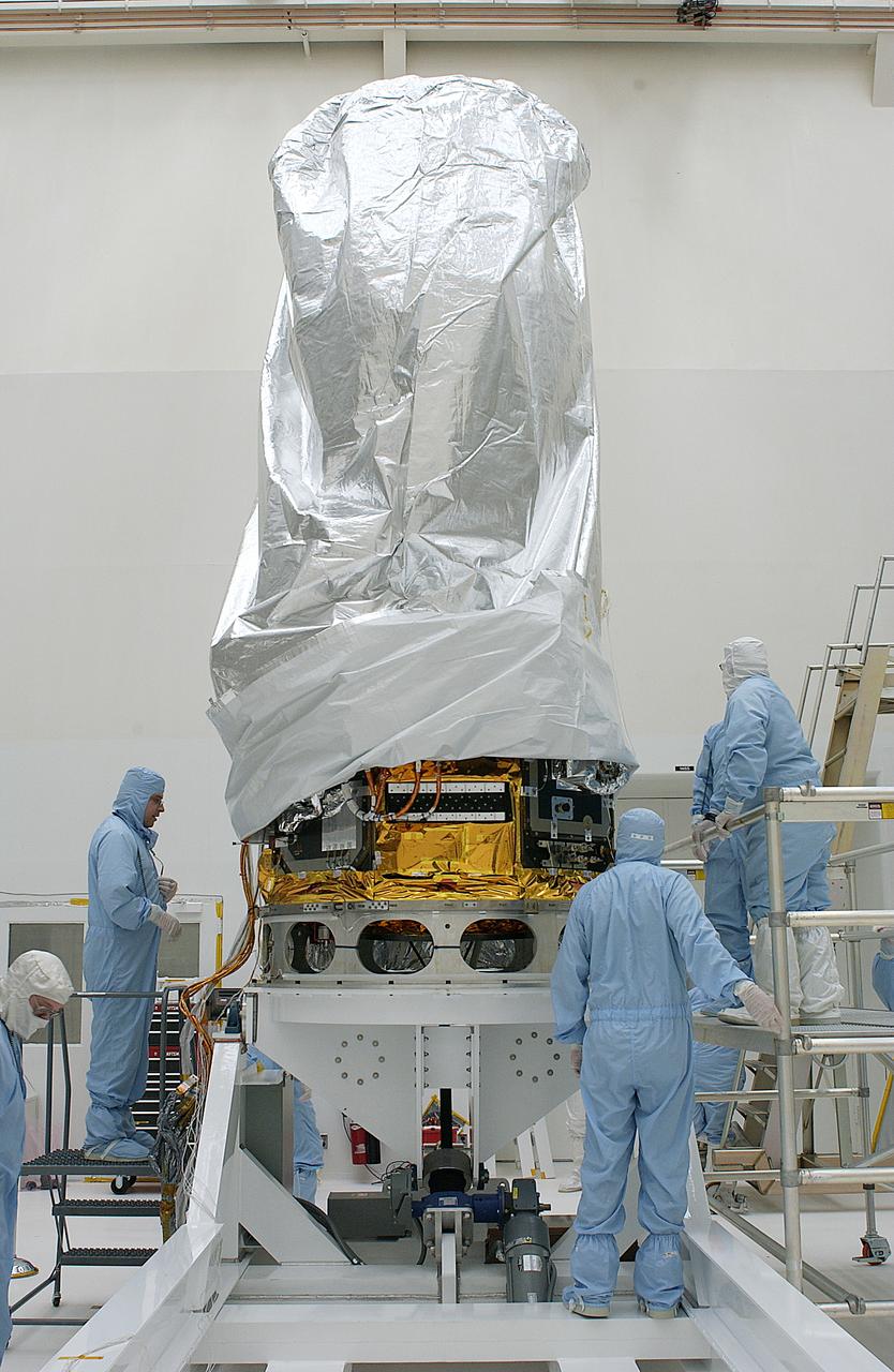 The Space Infrared Telescope Facility (SIRTF) is rotated to a vertical position in the clean room of Building AE today following its arrival from the Lockheed Martin plant in Sunnyvale, Calif. Final preparations for its launch aboard a Delta II rocket will now commence. SIRTF will obtain images and spectra by detecting the infrared energy, or heat, radiated by objects in space between wavelengths of 3 and 180 microns (1 micron is one-millionth of a meter). Most of this infrared radiation is blocked by the Earth's atmosphere and cannot be observed from the ground. Consisting of an 0.85-meter telescope and three cryogenically cooled science instruments, SIRTF is one of NASA's largest infrared telescopes to be launched. Its highly sensitive instruments will give a unique view of the Universe and peer into regions of space that are hidden from optical telescopes on the ground or orbiting telescopes such as the Hubble Space Telescope. SIRTF is scheduled for launch April 15 at 4:34:07 a.m. EDT from Launch Complex 17-B, Cape Canaveral Air Force Station.