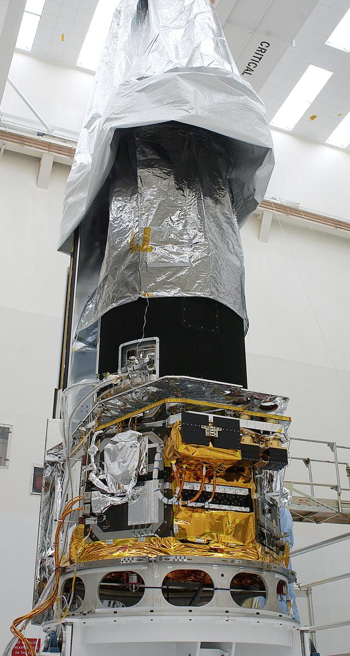 The Space Infrared Telescope Facility (SIRTF) is uncovered in the clean room of Building AE to permit workers access to the spacecraft to begin final preparations for its launch aboard a Delta II rocket. The observatory was shipped to Florida from the Lockheed Martin plant in Sunnyvale, Calif. SIRTF will obtain images and spectra by detecting the infrared energy, or heat, radiated by objects in space between wavelengths of 3 and 180 microns (1 micron is one-millionth of a meter). Most of this infrared radiation is blocked by the Earth's atmosphere and cannot be observed from the ground. Consisting of an 0.85-meter telescope and three cryogenically cooled science instruments, SIRTF is one of NASA's largest infrared telescopes to be launched. Its highly sensitive instruments will give a unique view of the Universe and peer into regions of space that are hidden from optical telescopes on the ground or orbiting telescopes such as the Hubble Space Telescope. SIRTF is scheduled for launch April 15 at 4:34:07 a.m. EDT from Launch Complex 17-B, Cape Canaveral Air Force Station.