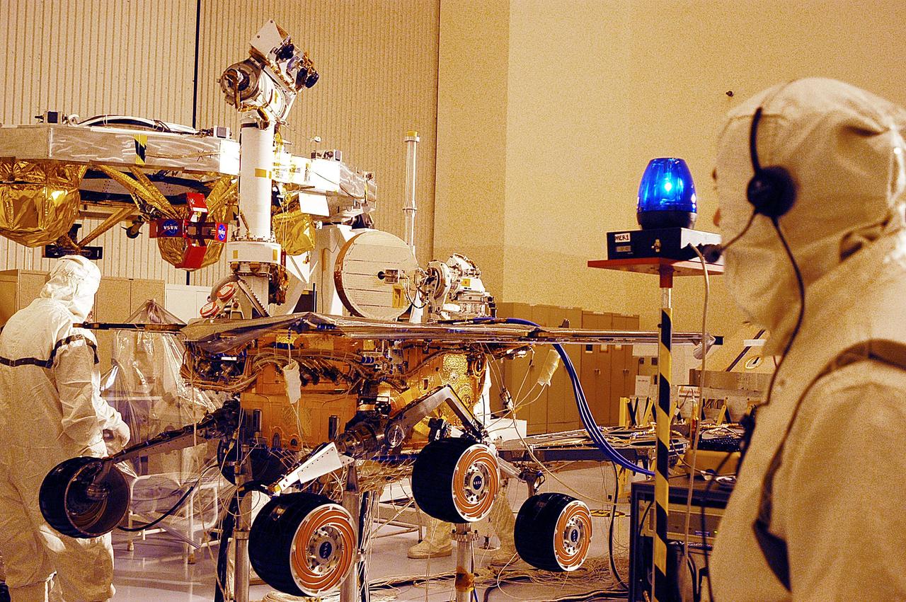 KENNEDY SPACE CENTER, Fla. - Workers in the Payload Hazardous Servicing Facility look over one of the two Mars Exploration Rovers, MER-2.  MER-1 and MER-2, their aeroshells and landers will undergo a full mission simulation before being integrated. After spin balance testing,  each spacecraft will be mated to a solid propellant upper stage booster that will propel the spacecraft out of Earth orbit. Approximately 10 days before launch they will be transported to the launch pad for mating with their respective Boeing Delta II rockets. The rovers will serve as robotic geologists to seek answers about the evolution of Mars, particularly  for a history of water. The rovers are identical to each other, but will land at different regions of Mars.  Launch of the first rover is scheduled for May 30 from Cape Canaveral Air Force Station.  The second will follow June 25.