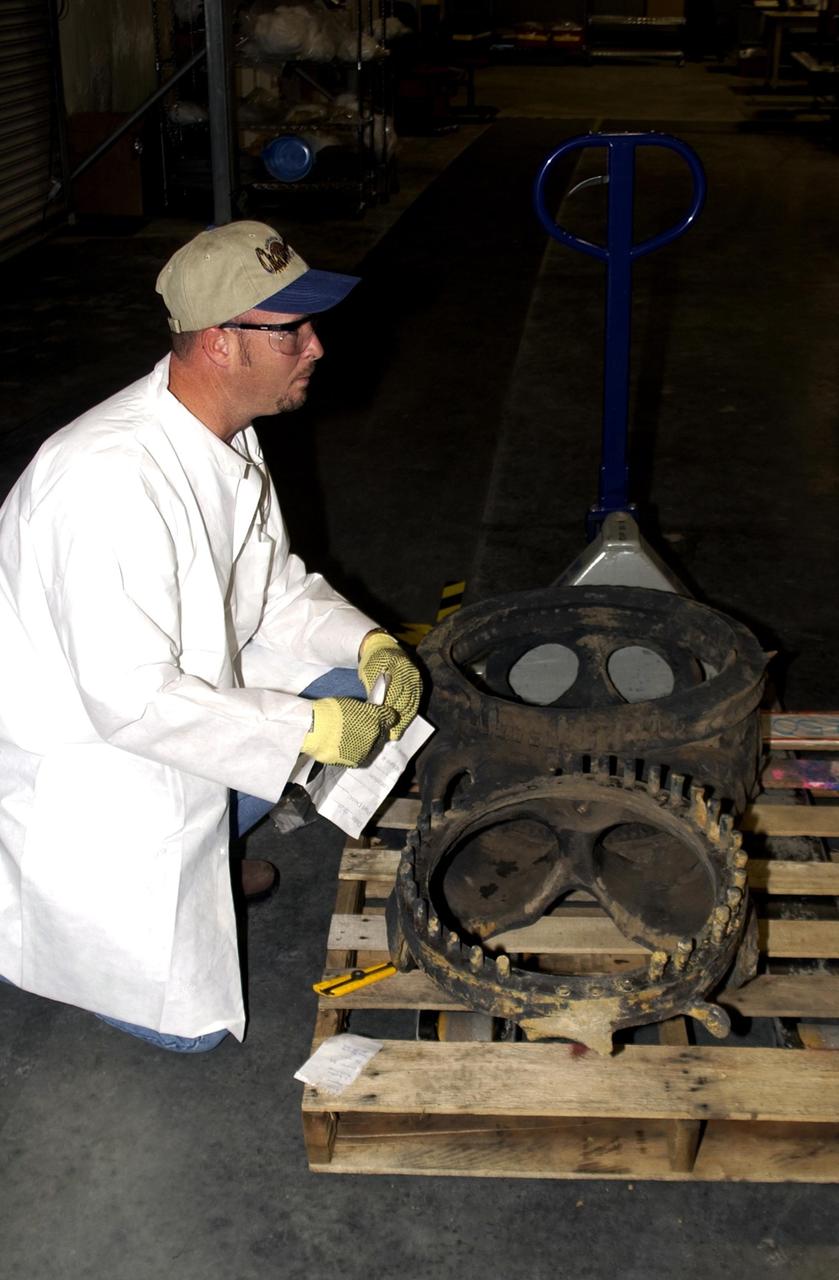 KENNEDY SPACE CENTER, Fla. - A member of the Columbia Reconstruction Project Team checks out a piece of Columbia debris newly arrived from Barksdale Air Force Base, Shreveport, La. Inside the RLV Hangar, the team is identifying pieces and placing them on a floor grid in a configuration of the orbiter. The team will attempt to reconstruct the bottom of the orbiter as part of the investigation into the accident that caused the destruction of Columbia and loss of its crew as it returned to Earth on mission STS-107. To date, 35,319 pieces have been shipped to KSC; 1,218 are identified and placed on the grid.