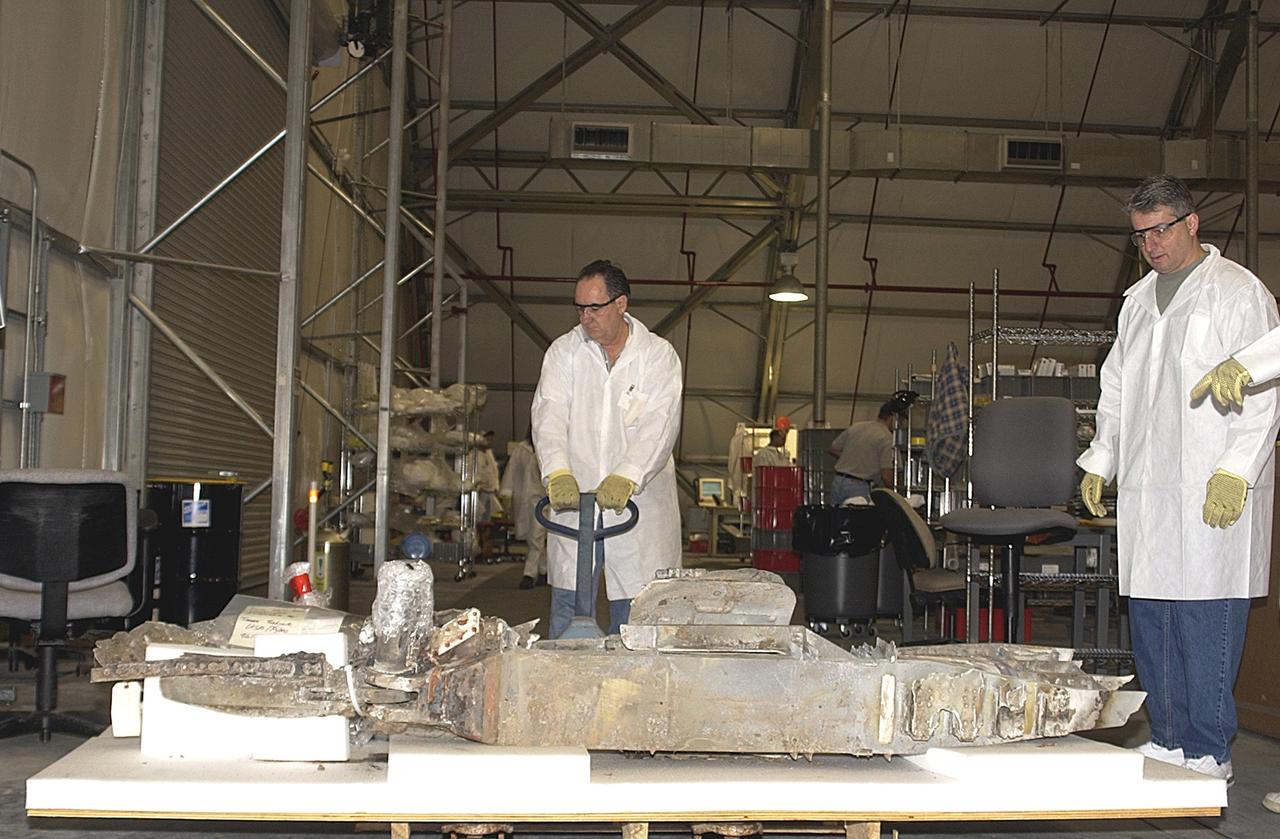 KENNEDY SPACE CENTER, Fla. - Members of the Columbia Reconstruction Project Team help move newly arrived pieces of Columbia debris into the RLV Hangar. There the team is identifying pieces and placing them on a floor grid in a configuration of the orbiter. The team will attempt to reconstruct the bottom of the orbiter as part of the investigation into the accident that caused the destruction of Columbia and loss of its crew as it returned to Earth on mission STS-107. To date, 35,319 pieces have been shipped to KSC; 1,218 are identified and placed on the grid.