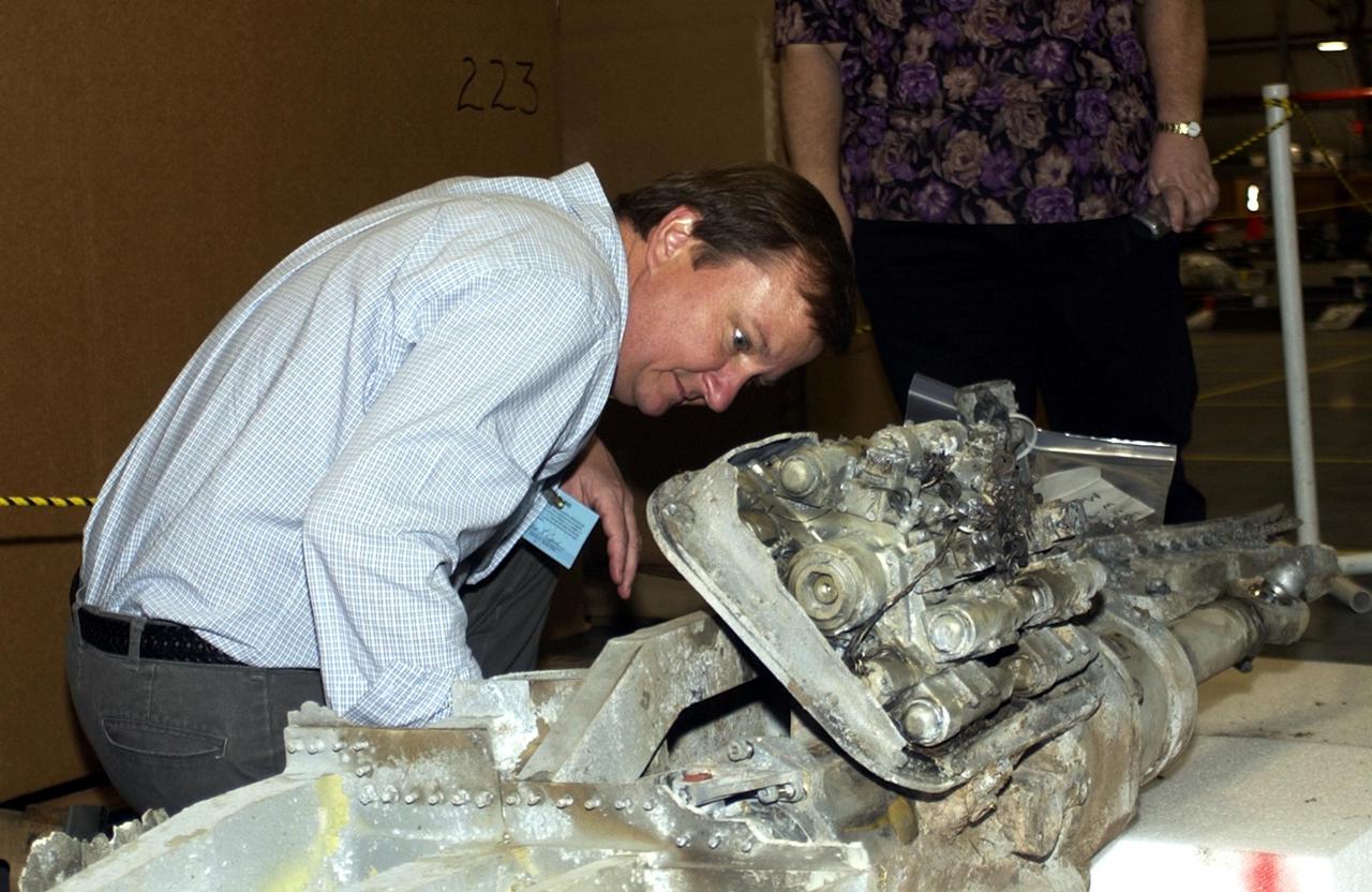 KENNEDY SPACE CENTER, Fla. -  Mike Leinbach, who is Shuttle launch director, looks closely at a piece of debris in the RLV Hangar.  To date, 35,319 pieces of debris have been shipped to KSC; 1,218 have been identified and placed on a grid in a configuration of the orbiter.  The team is attempting to reconstruct the bottom of the orbiter as part of the investigation into the accident that caused the destruction of Columbia and loss of its crew as it returned to Earth on mission STS-107.