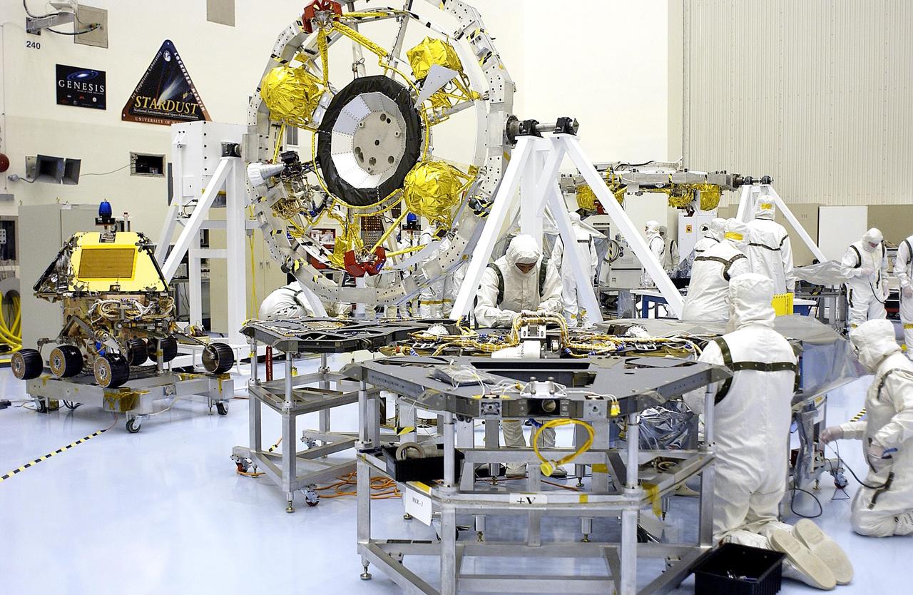 KENNEDY SPACE CENTER, Fla. - Workers in the Payload Hazardous Servicing Facility check out one of the landers for the Mars Exploration Rovers (MER).  In the background is the Cruise Stage Assembly.  Processing of the rovers, cruise stage, lander and heat shield elements is ongoing.  Set to launch in 2003, the MER Mission will consist of two identical rovers designed to cover roughly 110 yards each Martian day. Each rover will carry five scientific instruments that will allow it to search for evidence of liquid water that may have been present in the planet's past.  The rovers will be identical to each other, but will land at different regions of Mars.  The first rover has a launch window opening May 30, and the second rover a window opening June 25, 2003.