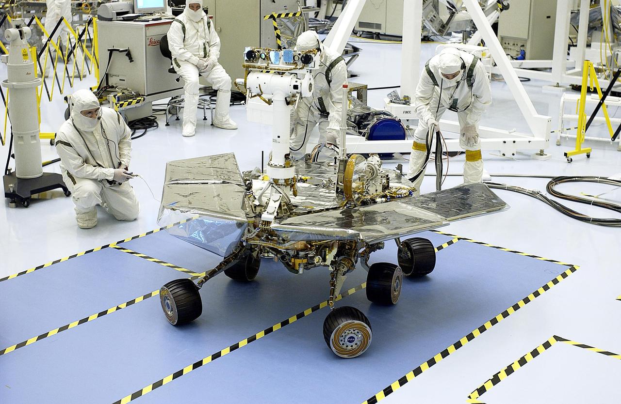 KENNEDY SPACE CENTER, Fla. - Workers in the Payload Hazardous Servicing Facility watch as the Mars Exploration Rover-2 (MER-2) turns. MER-2 is being tested for mobility and maneuverability. Atop the rover, on the left, can be seen the cameras, mounted on a Pancam Mast Assembly (PMA). On the right are the low-gain and high-gain antennas. Set to launch in Spring 2003, the MER Mission will consist of two identical rovers designed to cover roughly 110 yards each Martian day. Each rover will carry five scientific instruments that will allow it to search for evidence of liquid water that may have been present in the planet's past. The rovers will be identical to each other, but will land at different regions of Mars. The first rover has a launch window opening May 30, and the second rover a window opening June 25.