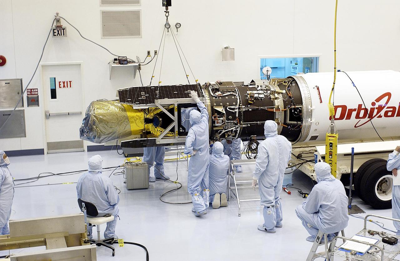 KENNEDY SPACE CENTER, Fla. - Workers in the Multi-Payload Processing Facility begin demating the Galaxy Evolution Explorer (GALEX) spacecraft from the Pegasus XL launch vehicle. Foreign object debris shields will be installed before its launch. The GALEX is an orbiting space telescope that will observe galaxies in ultraviolet light across 10 billion years of cosmic history. During its 29-month mission GALEX will produce the first comprehensive map of a Universe of galaxies under construction, bringing more understanding how galaxies like the Milky Way were formed. The GALEX launch date is under review.