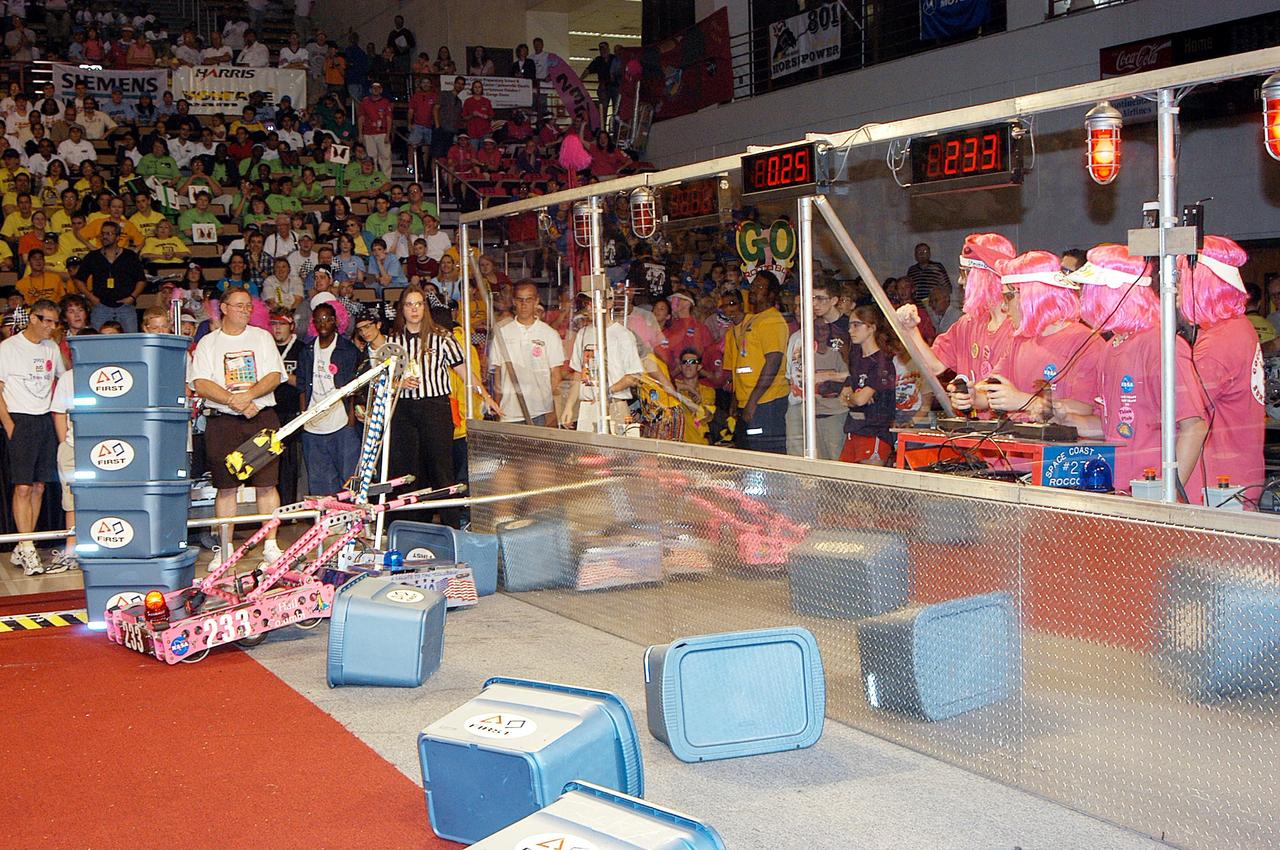 KENNEDY SPACE CENTER, FLA. - The NASA/Kennedy Space Center-sponsored student team (in pink wigs, right) demonstrates their robot's abilities during the 2003 Southeastern Regional FIRST Robotic Competition. The competition is being held at the University of Central Florida (UCF) in Orlando, March 20-23. Forty student teams from around the country are participating in the event that pits team-built gladiator robots against each other in an athletic-style competition. The teams are sponsored by NASA/Kennedy Space Center, The Boeing Company/Brevard Community College, and Lockheed Martin Space Operations/Mission Systems for the nonprofit organization For Inspiration and Recognition of Science and Technology, known as FIRST. The vision of FIRST is to inspire in the youth of our nation an appreciation of science and technology and an understanding that mastering these disciplines can enrich the lives of all mankind.