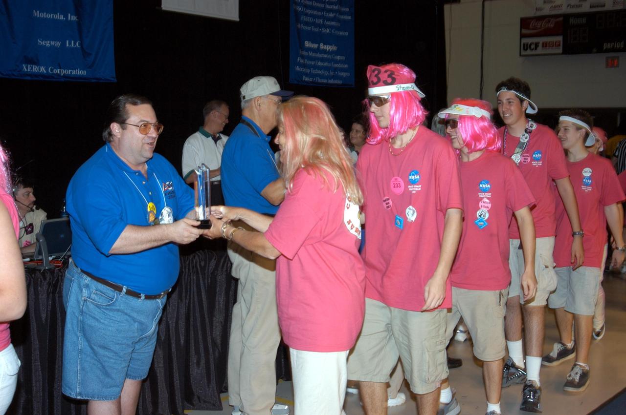 KENNEDY SPACE CENTER, FLA. - The NASA/Kennedy Space Center-sponsored student team (in pink wigs) is congratulated by the judges of the 2003 Southeastern Regional FIRST Robotic Competition. The competition is being held at the University of Central Florida (UCF) in Orlando, March 20-23. The team won awards for Regional Finalist 2, GM Industrial Design and the Imagery Award. Forty student teams from around the country are participating in the event that pits team-built gladiator robots against each other in an athletic-style competition. The teams are sponsored by NASA/Kennedy Space Center, The Boeing Company/Brevard Community College, and Lockheed Martin Space Operations/Mission Systems for the nonprofit organization For Inspiration and Recognition of Science and Technology, known as FIRST. The vision of FIRST is to inspire in the youth of our nation an appreciation of science and technology and an understanding that mastering these disciplines can enrich the lives of all mankind.